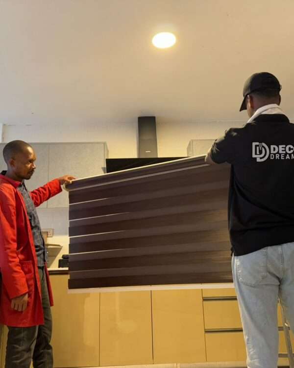 Two employees preparing blinds for window installation.